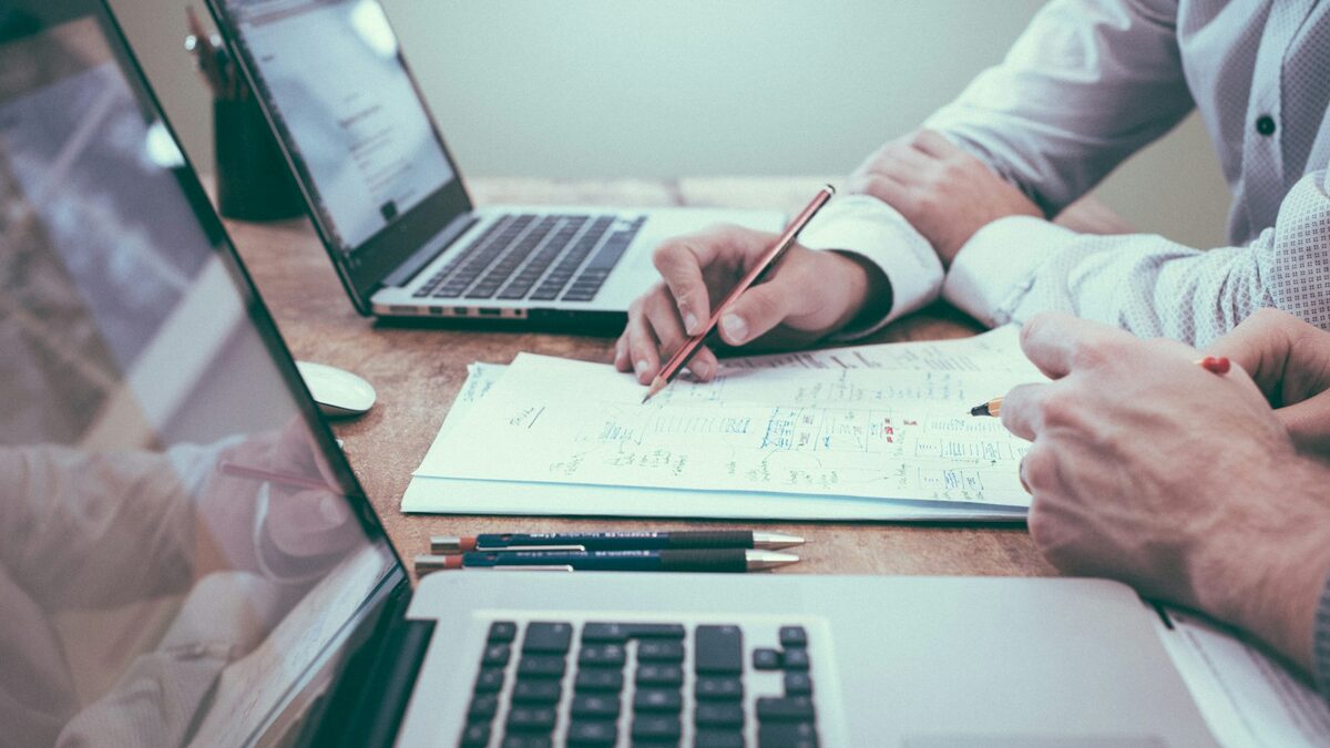 Types of work permits in Canada: open, employer-specific, PGWP and more Person reviewing immigration paperwork at a desk with a laptop and a small Canadian flag
